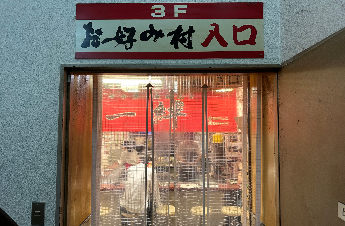 Dörr med genomskinligt plastskynke in till en restaurang med bardisk. Ovanför dörren lyder texten "3F" följt av japansk skrift.