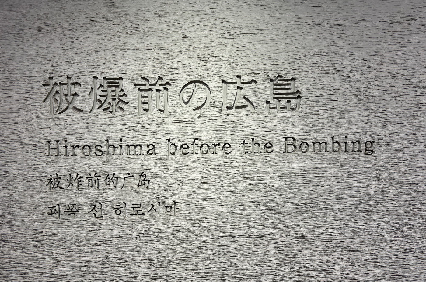 Grå stenvägg med urgröpta bokstäver som lyder "Hiroshima before the bombing".