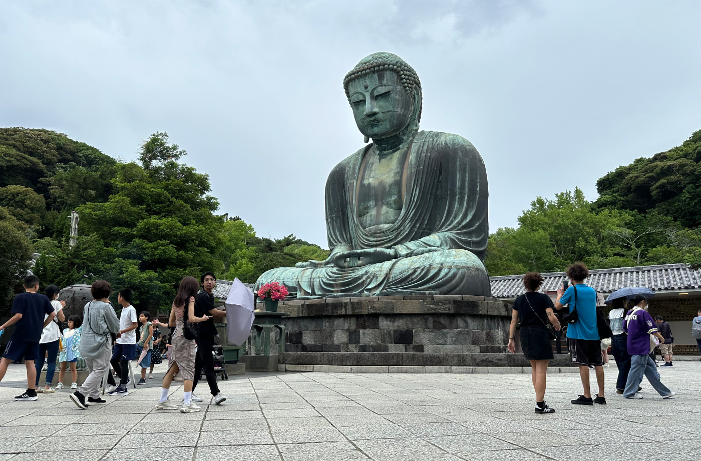 Enorm staty på en grön buddha mitt på ett öppet torg. Runt statyn står folk och tittar på den och fotograferar.