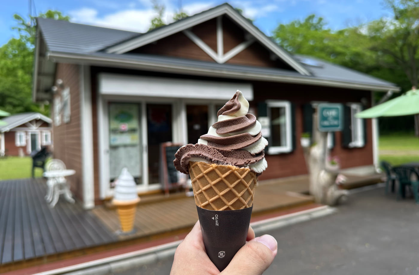 Choklad- och vaniljglass i strut framför ett brunt hus med vita knutar.