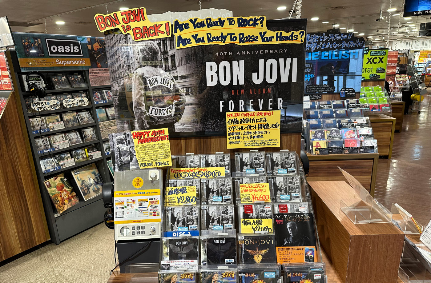 Liten skivhylla med Bon Jovis nya album. Mycket text. En del lyder "40th anniversary. Bon Jovi. New album. Forever".